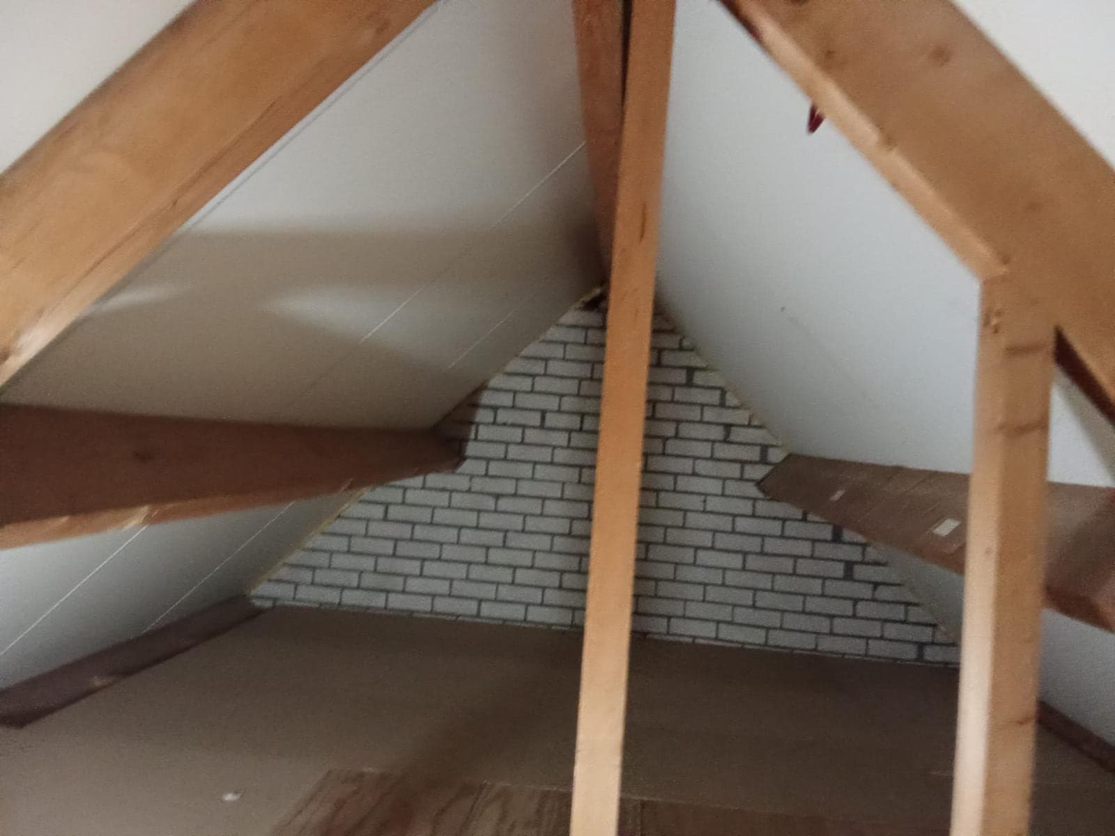 Zolder met houten spanten en witte dakplaten, voor het isoleren