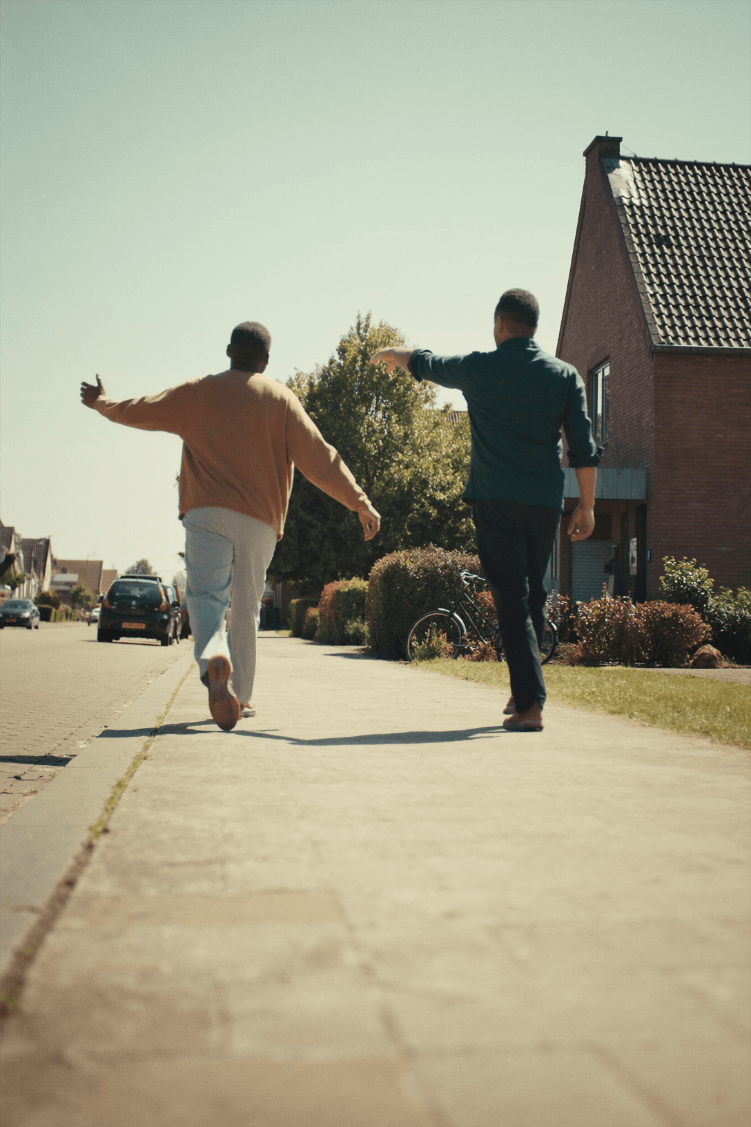 Twee mannen lopen samen door een woonstraat en kijken naar een woning