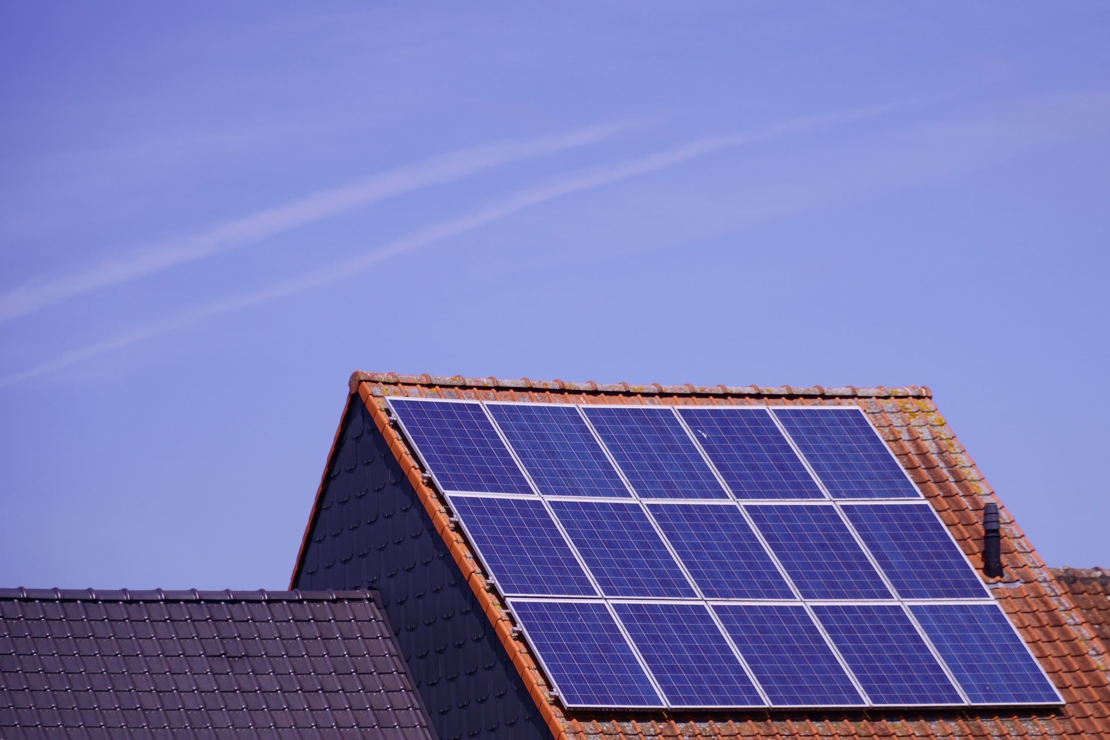 Geplaatste zonnepanelen op een schuin dak tegen een blauwe lucht